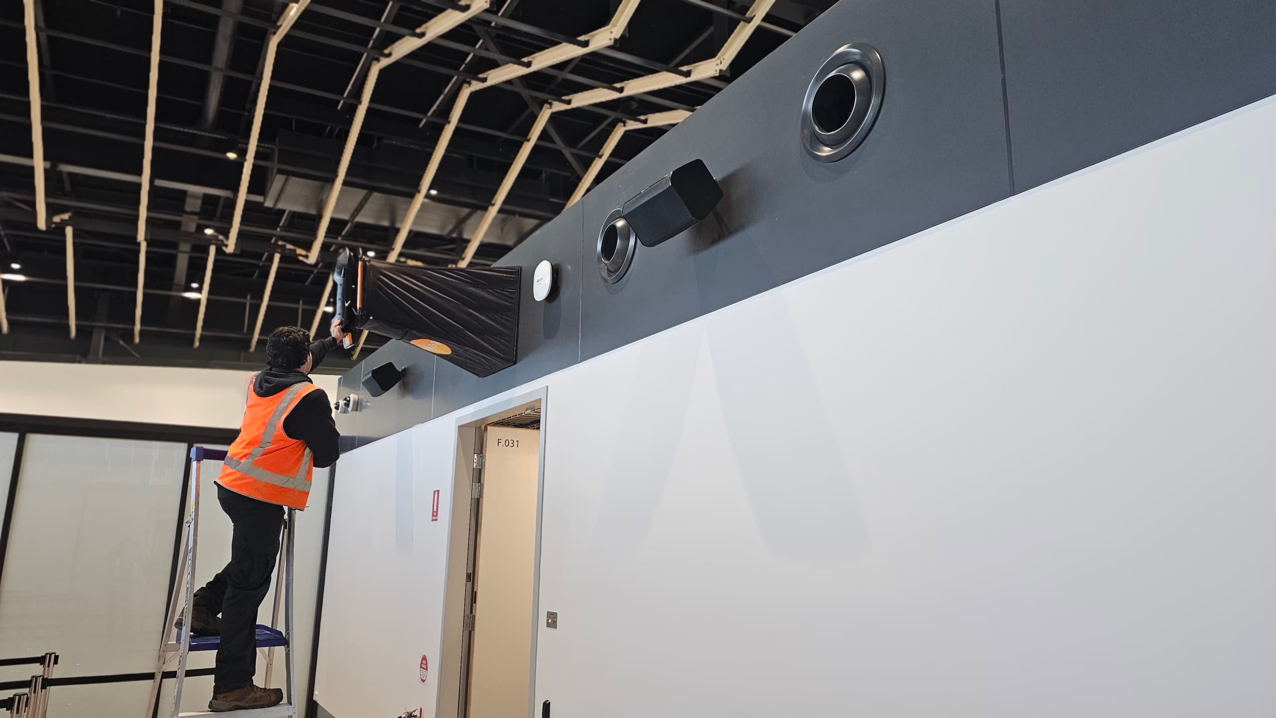 ENGIC technician performing professional air balancing using a Testo air balancing hood in a commercial building