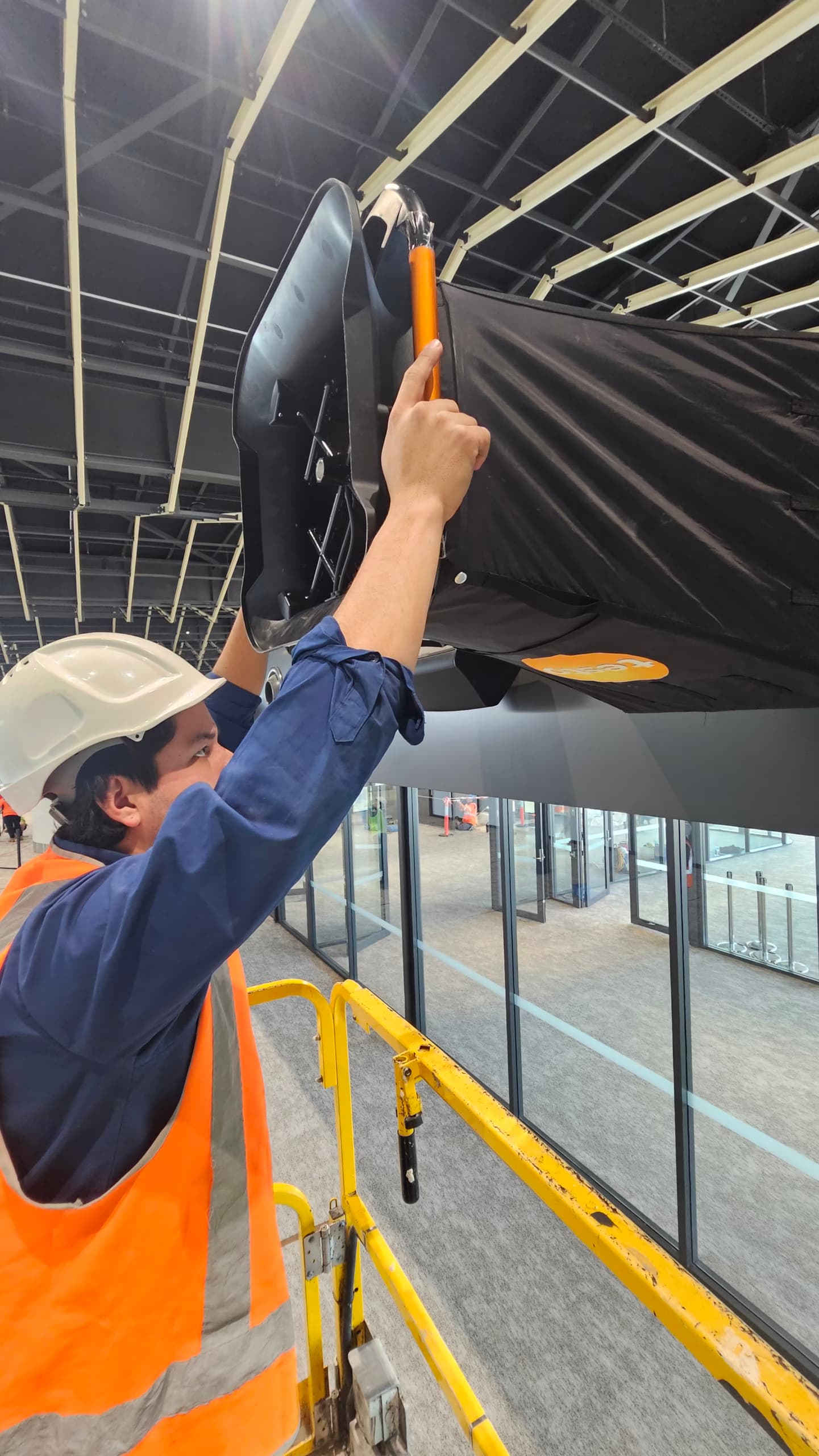 ENGIC technician installing ductwork insulation at height during an airport terminal HVAC project